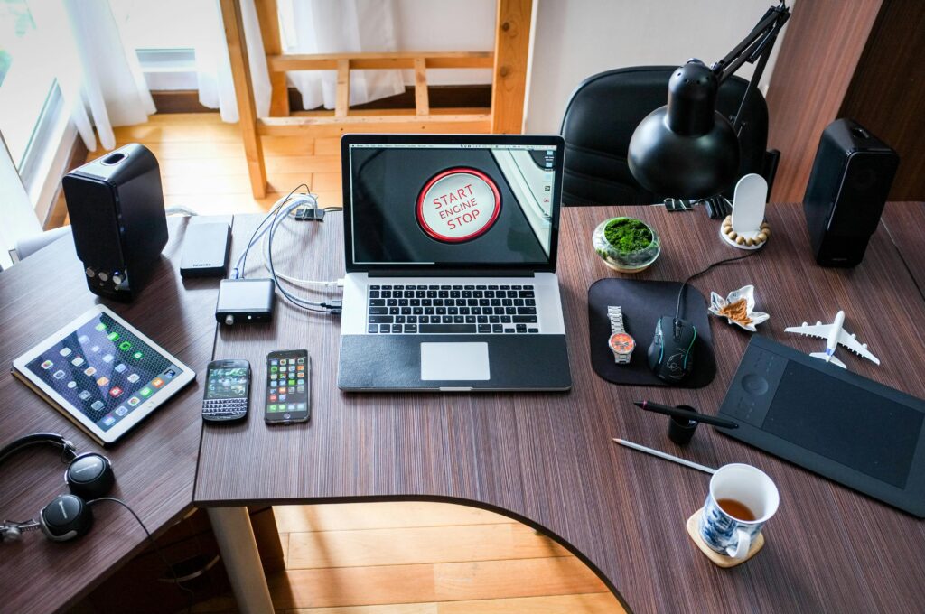 Un bureau contemporain aménagé avec des ordinateurs portables, des gadgets et des accessoires, créant un lieu de travail à la pointe de la technologie.